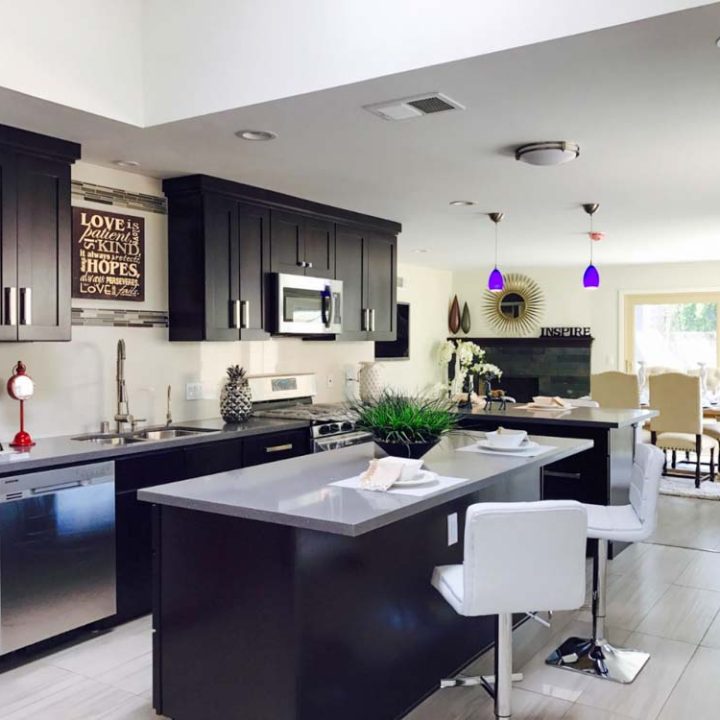 a kitchen in black and white with two white high chairs and a kitchen island.